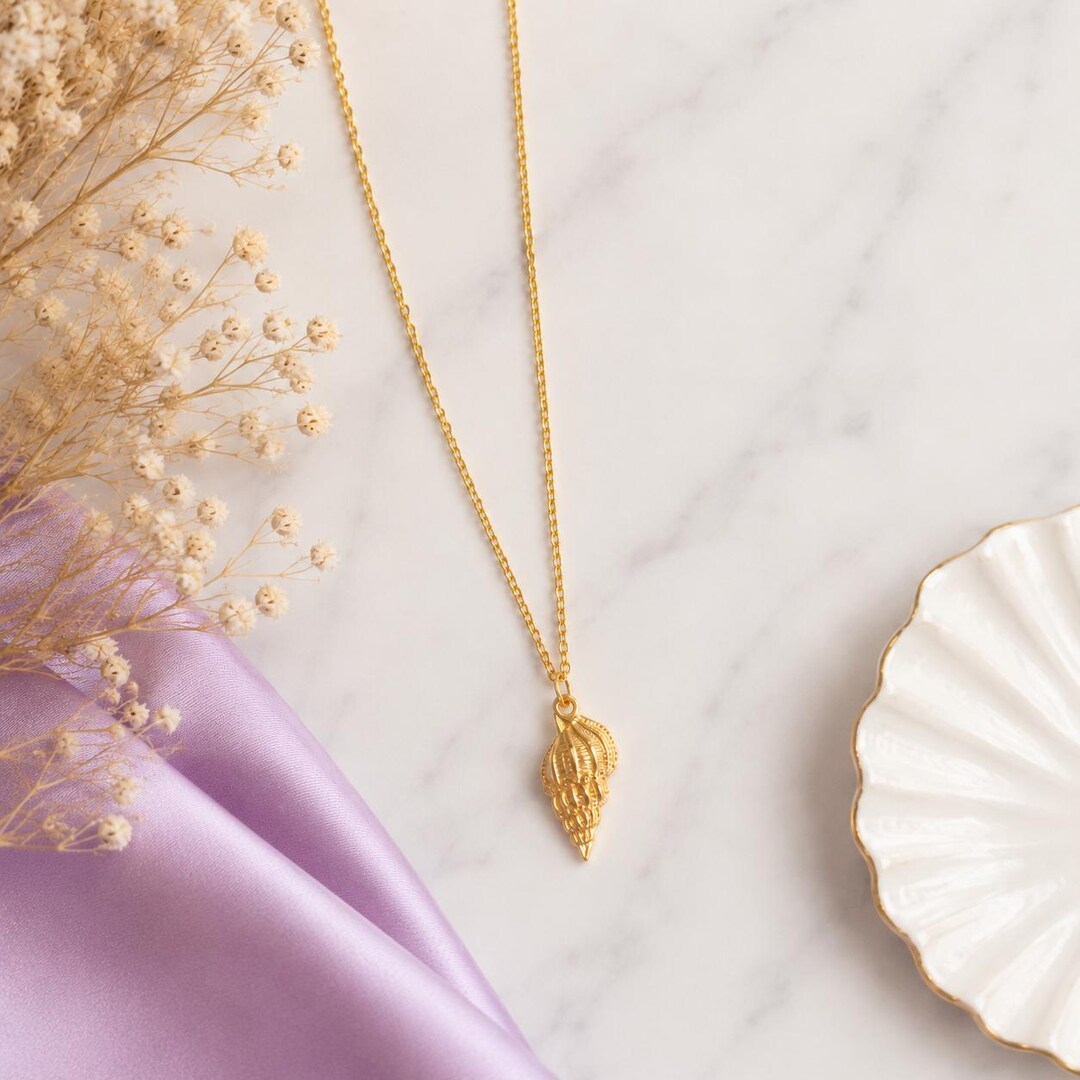 Gold conch shell pendant necklace on a delicate gold chain