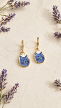 Gold huggie hoop earrings with oval blue cat face charms