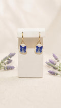 Gold huggie dangle earrings with oval blue dog charms