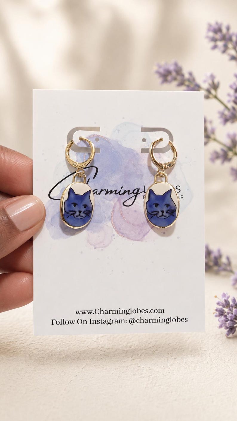 Blue cat charm earrings displayed on a Charming Lobes earring card